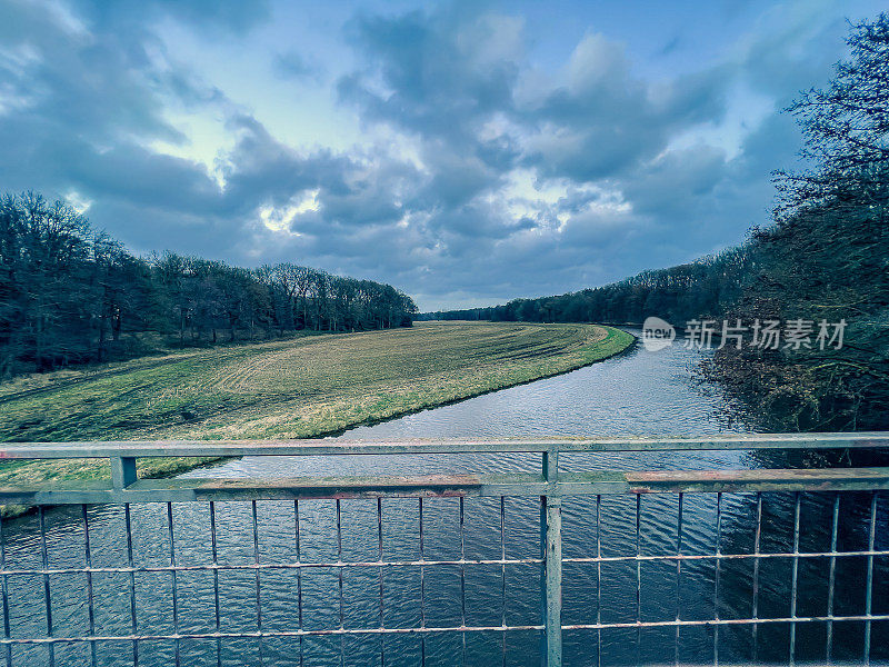 在德国，从一座桥上看到的河流被称为“Große Aa”，旁边是一片田野和一片森林。
